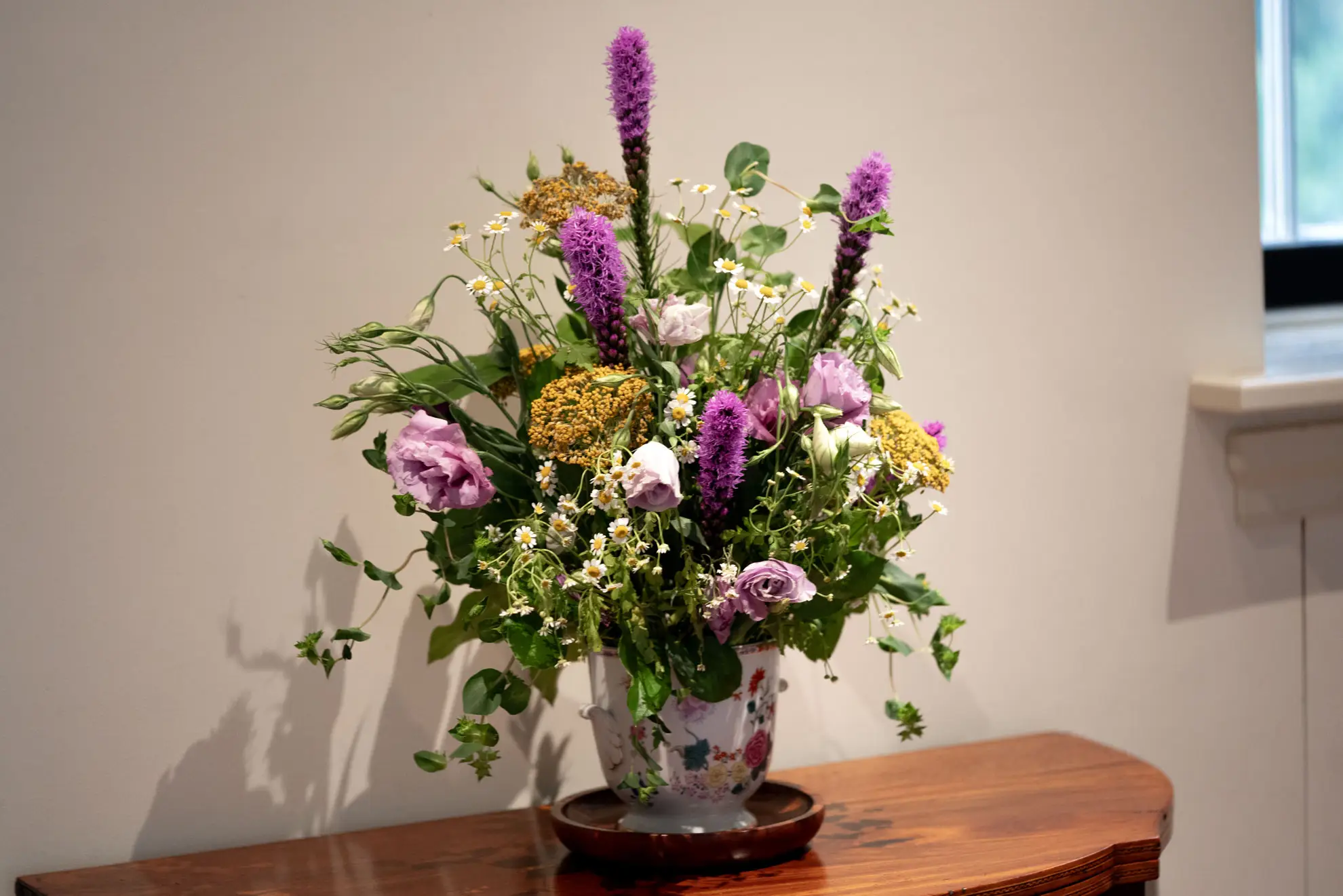 Blazing star spikes in a vase bouquet of pink, purple and white flowers on a wooden table