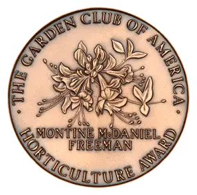 Bronze circular horticulture award medal with a floral relief; reads 'The Garden Club of America' around the edge and 'Montine McDaniel Freeman' in the center.